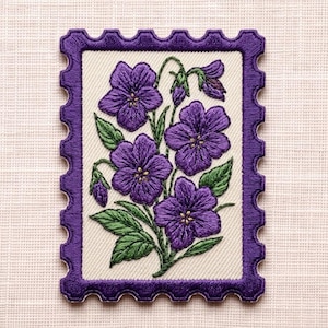 May include: A rectangular embroidered patch shaped like a postage stamp with a scalloped border in deep purple. The center features a detailed botanical design of four purple violet flowers with yellow centers and green leaves on a cream background.