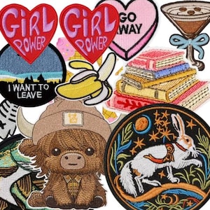 Peut inclure: Une collection d'&eacute;cussons brod&eacute;s de diff&eacute;rentes formes et motifs. Comprend des &eacute;cussons en forme de c&oelig;ur avec le texte "GIRL POWER", un &eacute;cusson rond avec "I WANT TO LEAVE", une pile de livres, une vache des Highlands et un lapin avec un motif floral.