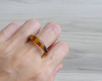 May include: A brown and black tortoiseshell ring.