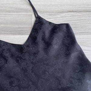 Closeup of the silky polyester fabric in black featuring a woven paisley texture & subtle sheen