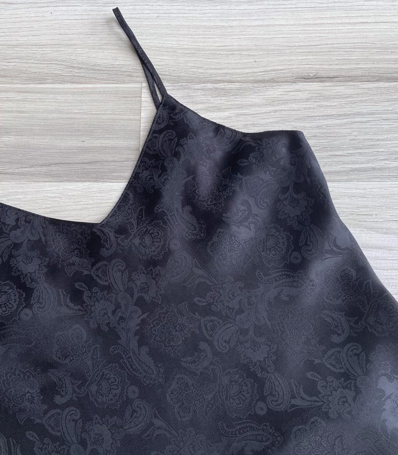 Closeup of the silky polyester fabric in black featuring a woven paisley texture & subtle sheen