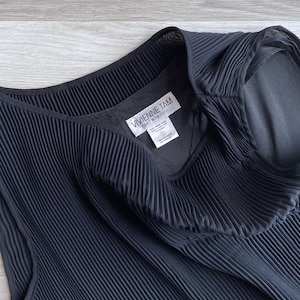 May include: Black sleeveless dress with a pleated design and a white label that reads "VIVIENNE TAM EAST WIND CODE".