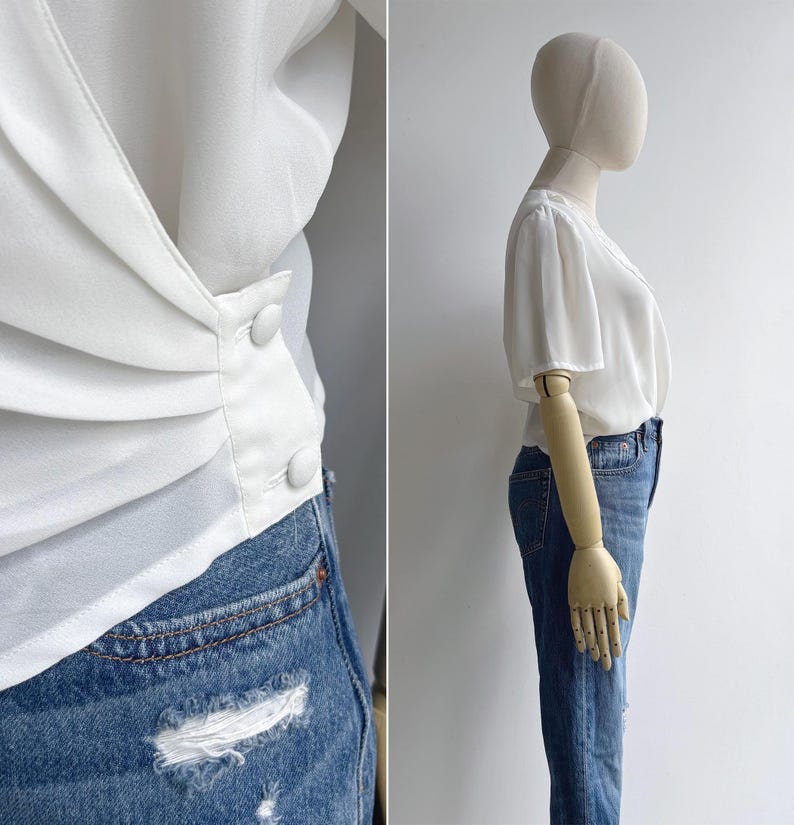 Side view of a mannequin in a retro 80s white polyester chiffon draped top with a feminine sheer lace collar. The left side of the image shows a close-up of the pleated waist detail & buttons.