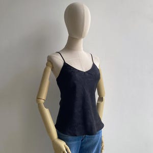 Angled view of a mannequin wearing a 90s/Y2K vintage babydoll going out cami tank with a bias draped fit, skinny spaghetti straps & a slight v-neck