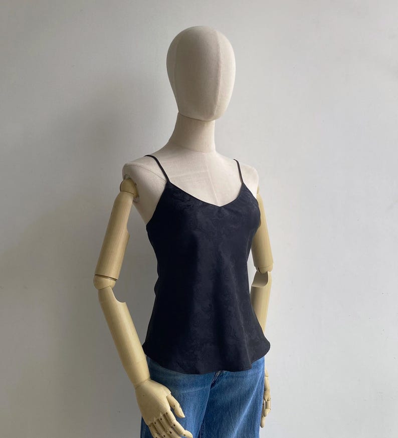 Angled view of a mannequin wearing a 90s/Y2K vintage babydoll going out cami tank with a bias draped fit, skinny spaghetti straps & a slight v-neck