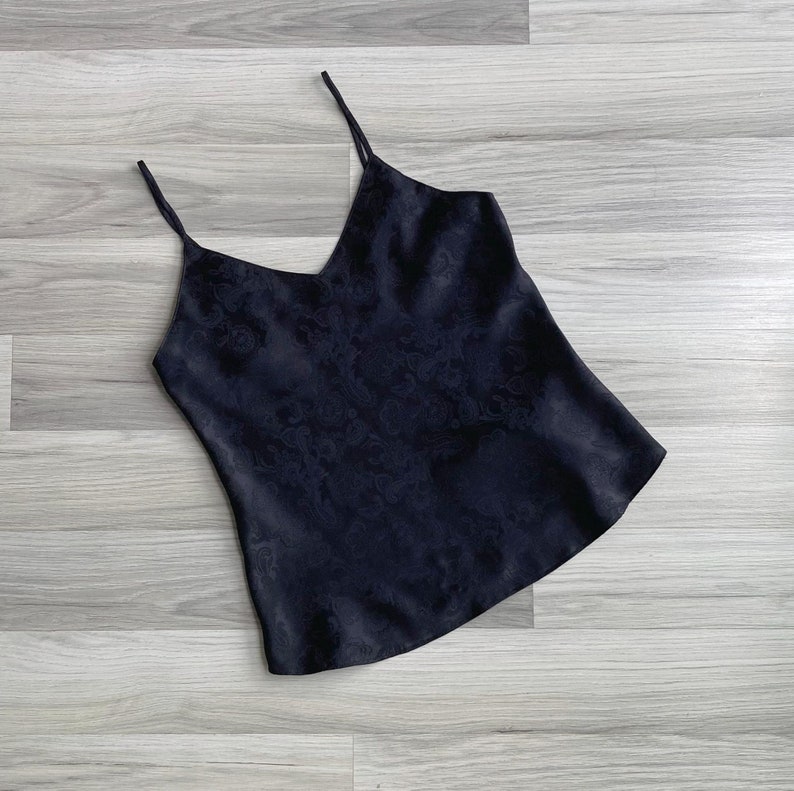 Flat lay of a 1990s vintage black silky camisole with a woven paisley texture & skinny spaghetti straps