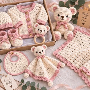 May include: A crochet baby gift set featuring a cream and pink cardigan, matching beanie, booties, and bib. Includes a stuffed bear, a bear-shaped wooden rattle, and a security blanket. A wooden sign reads Made with Love and a tag reads Sweet Baby.