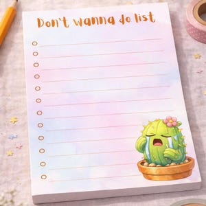 May include: A notepad with the text "Don't wanna do list" in orange script. The notepad has a watercolor background and a cartoon cactus illustration. The cactus is crying and wearing a flower. The notepad has lines for writing.