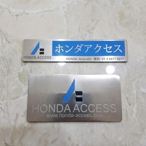 May include: Two silver metal name tags. The top tag has the text "HONDA ACCESS" and Japanese characters, with a blue and black logo. The bottom tag reads "HONDA ACCESS" and "www.honda-access.com" with the same logo.