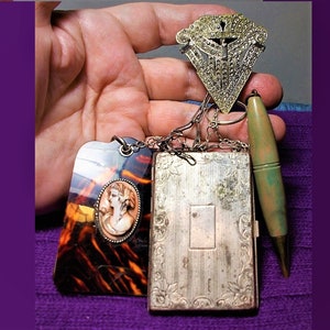 May include: A set of vintage jewelry including a silver locket with an ornate design, a tortoiseshell pendant with a cameo, a silver and rhinestone brooch, and a green wooden pencil.