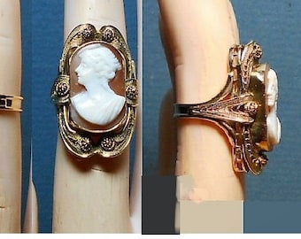 May include: A gold ring with a cameo of a woman's profile. The cameo is set in a gold frame with intricate details. The ring is worn on a finger.