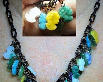 May include: A black chain necklace with multiple colorful glass charms. The charms are in various shapes and sizes, including flowers, hearts, and geometric shapes. The necklace is a statement piece and would be a great addition to any jewelry collection.