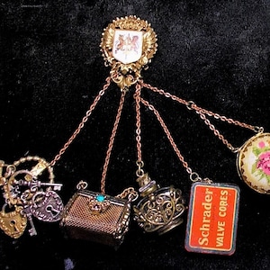 May include: A gold charm bracelet with a variety of charms, including a small purse, a bottle, a key, a lock, and a small box with the text "Schrader Valve Cores".