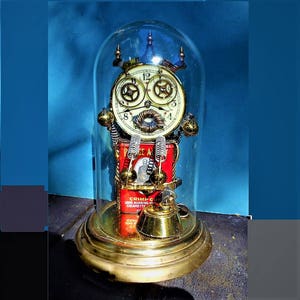 May include: A steampunk-style clock with a brass finish, encased in a glass dome. The clock features a red and white cigarette pack with the text "CRIMP CUT LONG BURNING CIGARETTE" and a vintage-style telephone receiver.