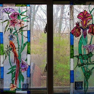 May include: Two stained glass panels depicting floral arrangements. The left panel features a red bird, pink flowers, and green leaves. The right panel features a purple iris, a pink morning glory, and green leaves.