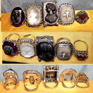 May include: A collection of ten antique rings featuring a variety of designs and materials. The rings include cameo portraits, religious symbols, and colourful gemstones. Some rings are made of gold, silver, and other metals.