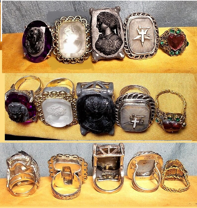May include: A collection of ten antique rings featuring a variety of designs and materials. The rings include cameo portraits, religious symbols, and colourful gemstones. Some rings are made of gold, silver, and other metals.