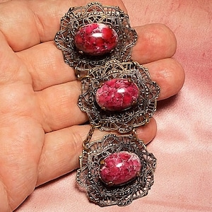 May include: A vintage bracelet with three pink and white cameo-like stones set in ornate gold-toned filigree.