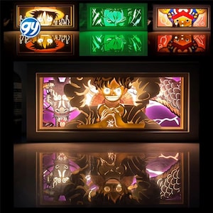 May include: A series of illuminated shadow boxes with anime character designs. The boxes have wooden frames and feature intricate cut-out artwork with bright colours. The top row shows Luffy, while the bottom row displays a larger, detailed scene of Luffy with a dragon.