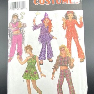 May include: A Simplicity Costumes sewing pattern envelope, number 0944, featuring illustrations of five different outfits: a pink genie costume, a purple bat-print witch costume, a red star-print devil costume, a green floral dress, and a hippie outfit.