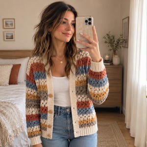 May include: A long-sleeve crochet cardigan featuring horizontal stripes in rust orange, dusty blue, mustard yellow, and cream. The garment has a cream-colored button-down front placket, a V-neckline, and ribbed cuffs and hem in a solid cream knit.