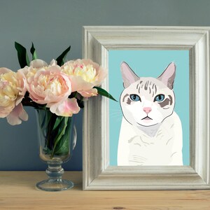 May include: A white and grey cat with blue eyes is looking directly at the camera. The cat is in a white frame with a light blue background.