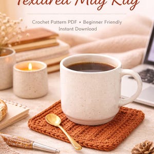 Op de afbeelding: Een witte mok gevuld met koffie staat op een getextureerde, roestkleurige gehaakte mokkenrug. Een gouden lepel ligt op de rug. De afbeelding bevat een brandende kaars, een pen en de tekst "Textured Mug Rug".