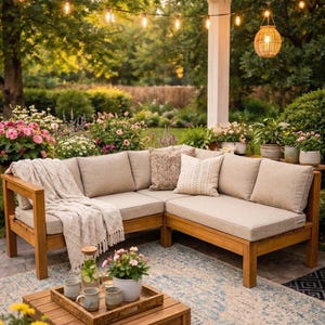 May include: An outdoor living space featuring a wooden sectional sofa with beige cushions and throw pillows. A wooden coffee table holds a tray with mugs and a water carafe. The scene is illuminated by string lights and a hanging wicker lamp.