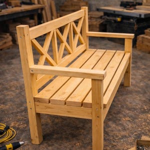 Könnte beinhalten: Eine hellfarbene Holzbank mit einer Sitzfläche aus Latten und einer Rückenlehne mit einem Kreuzmuster. Die Bank hat Armlehnen und ist mit sichtbaren Schrauben konstruiert. Der Hintergrund zeigt eine Werkstatteinstellung mit Werkzeugen und Holz.