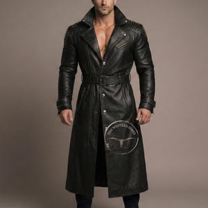 以下が含まれることがあります： 黒い革のトレンチコート。ウエストベルト、スタッズ付きの肩、ノッチドラペルカラーが特徴です。コートはボタンダウンフロントで、右下にロゴがあります。