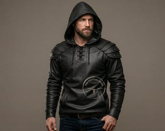 May include: A black hooded pullover featuring a lace-up neckline, long sleeves, and layered shoulder armor plates with metallic studs. A circular logo with the text THE WESTERN HIDES and a longhorn skull graphic is visible on the chest.