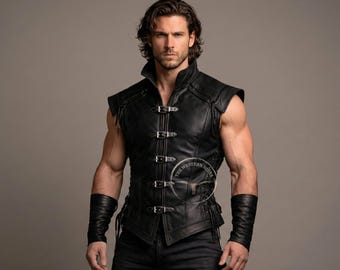 Può includere: Gilet in pelle nera con collo alto e fibbie multiple. Il gilet ha un design senza maniche ed è abbinato a polsini neri coordinati. Il logo The Western Hides è visibile sul gilet.