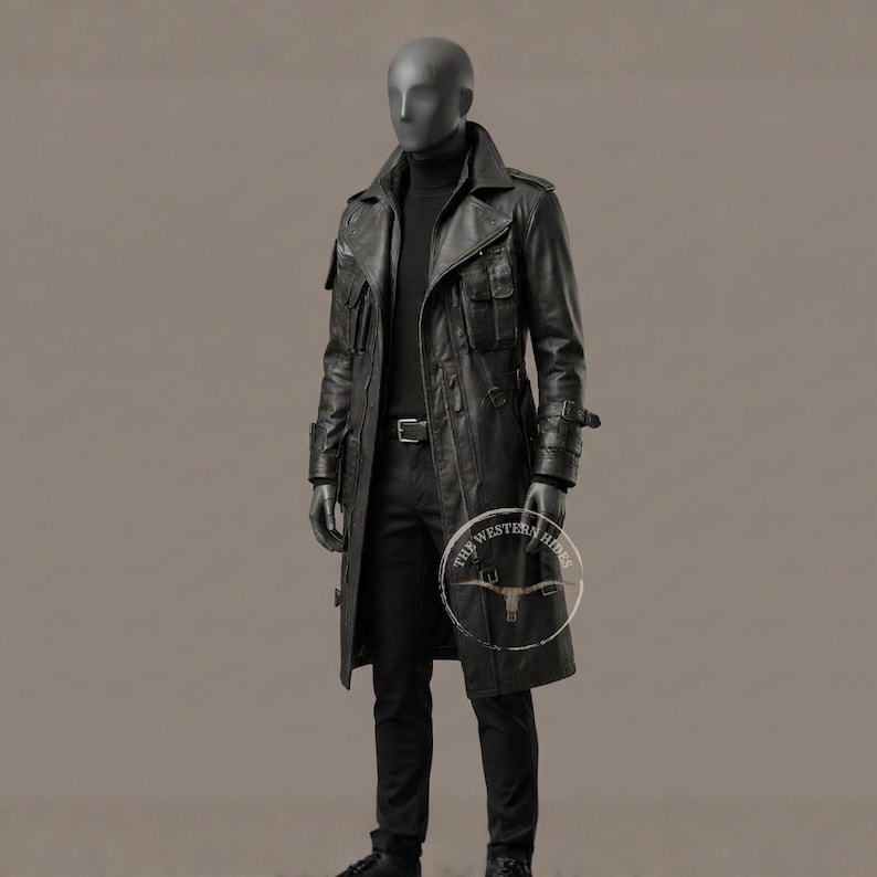 May include: A black leather trench coat with multiple pockets, a belt, and a high collar. The coat is worn over a black turtleneck and pants. The mannequin is wearing black gloves. The coat has the text "THE WESTERN RIDES" on the lower right side.