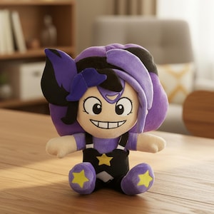 Può includere: Bambola di peluche con un viso sorridente, capelli viola e dettagli neri. La bambola indossa una tuta nera con una stella gialla e scarpe viola con stelle gialle. La bambola è seduta su una superficie di legno.