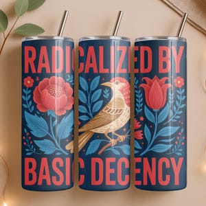 May include: Three navy blue insulated tumblers with silver straws. Each tumbler features a floral design with a bird and the words "RADICALIZED BY BASIC DECENCY" in red. The tumblers are decorated with red flowers and blue leaves.