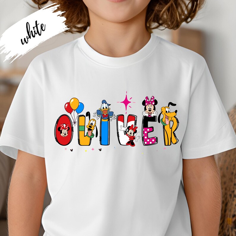 Op de afbeelding: Wit T-shirt met de naam "OLIVER" in kleurrijke Disney-letters. Elke letter is versierd met een ander Disney-personage, waaronder Mickey en Minnie Mouse, Donald Duck en Pluto. Het woord "white" is in cursiefschrift linksboven geschreven.