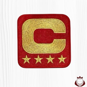 May include: A white ceramic mug with a black handle and the text "But First, Coffee" in a bold, black font. The mug is set against a blurred background, suggesting a cozy setting.