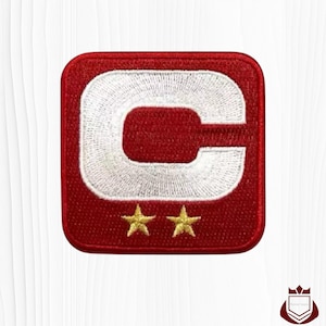 May include: A red and white embroidered patch with a large white "C" in the center. Two gold stars are below the letter. The patch has a square shape with rounded corners.