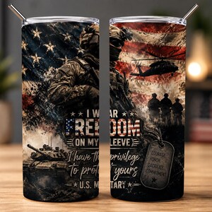 Puede incluir: Un vaso cilíndrico de metal con pajita, con un gráfico de un soldado, un tanque, un helicóptero y la bandera estadounidense. El texto dice: I WEAR FREEDOM ON MY SLEEVE I have the privilege To protect yours U.S. MILITARY. Una placa de identificación muestra: COURAGE, HONOR, SACRIFICE, COMMITMENT.