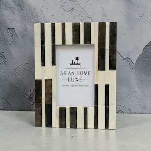 Peut inclure: Cadre photo rectangulaire avec un motif à rayures crème et marron foncé. Le cadre a un intérieur blanc et présente le texte "ASIAN HOME LUXE" avec un logo. Le cadre est conçu pour la décoration intérieure.