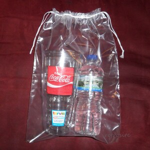 May include: A clear plastic drawstring bag with a white drawstring. Inside the bag is a clear tumbler with a red Coca-Cola logo and a clear plastic water bottle with a blue cap and a white label that says "Glacier Mist Spring Water".