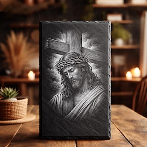 Könnte beinhalten: Schwarz-weiß-Porträt von Jesus mit Dornenkrone, vor einem Holzkreuz und einem bewölkten Himmel. Das Bild ist auf einer rechteckigen Schieferplatte gedruckt, die sich zur Präsentation eignet.