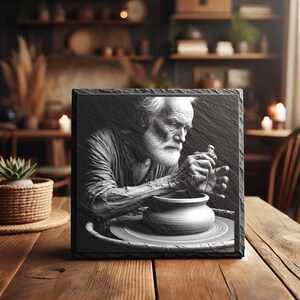 May include: A square black slate plaque featuring a black and white image of an elderly person with a beard shaping a clay pot on a pottery wheel. The plaque has a rough, chiseled edge texture and displays a detailed monochromatic scene of a craftsperson.