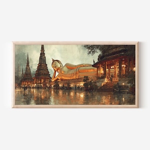 May include: A framed horizontal wall art print depicting a large golden reclining Buddha statue situated next to a traditional temple structure with tall spires. The scene features warm lighting, dark architectural details, and a reflective ground surface.