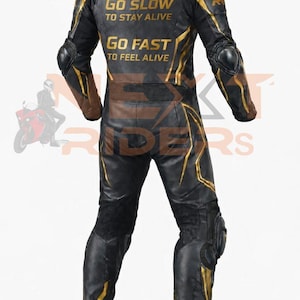Op de afbeelding: Zwart en goud motorracepak met beschermende padding op de schouders, ellebogen en knie&euml;n. Het pak heeft gouden accenten en de tekst "GO SLOW TO STAY ALIVE" en "GO FAST TO FEEL ALIVE" op de rug.