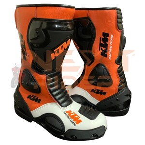 Puede incluir: Un par de botas de carreras de motos en color naranja, blanco y negro con el logotipo de KTM Racing Team. Las botas tienen un diseño de corte alto con paneles protectores negros, secciones de cuero naranja texturizado y punteras blancas.