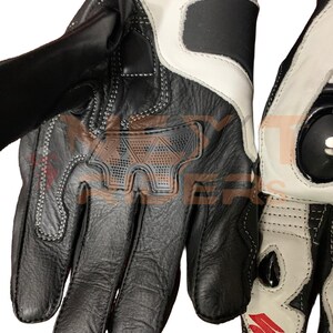 May include: Black and white motorcycle gloves with reinforced knuckles and palm padding. The gloves feature a leather construction with white accents and stitching. The gloves have a velcro strap closure and a Suzuki logo.