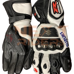 May include: Pair of black and white leather motorcycle gloves with the Suzuki logo in blue and silver. The gloves have reinforced knuckles and the GSX logo in red. The gloves are designed for protection and performance.