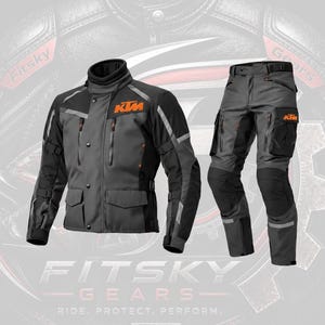 Könnte beinhalten: Ein Motorradjacken- und Hosenset in Anthrazit und Schwarz. Die Jacke verfügt über einen hohen Kragen, Vordertaschen und das orangefarbene KTM-Logo auf der Brust. Die passende Hose hat seitliche Cargotaschen und schwarze Knieverstärkungen.