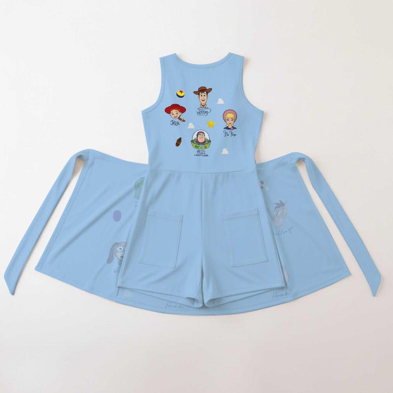 May include: A light blue sleeveless romper featuring two front pockets and a graphic print of Toy Story characters including Woody, Jessie, Bo Peep, and Buzz Lightyear, with their names printed below each character and small star and cloud icons.
